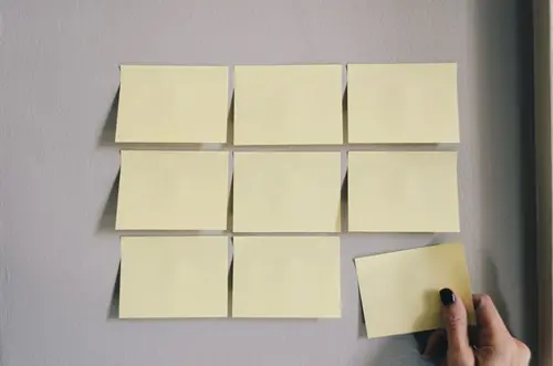 post it notes in rows with hand grabbing one
