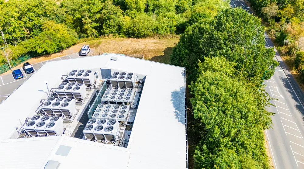Aerial view of heating system on top of a building surrounded by green trees