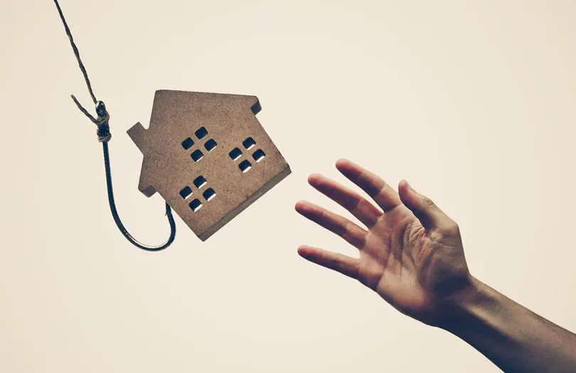 Wooden house on fishing line with hand reaching to it
