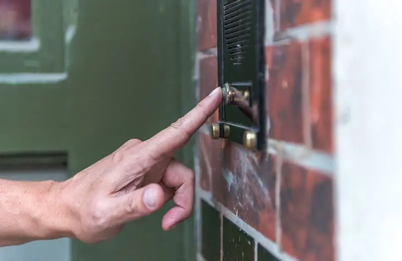 A hand ringing a doorbell