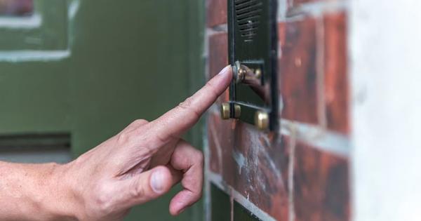 A hand ringing a doorbell