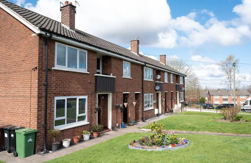 View of a row of houses converted into flats with gardens at the front. 