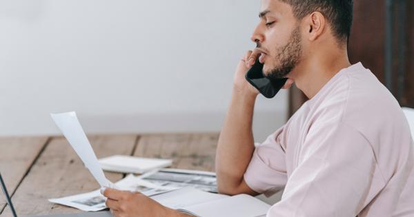 man with phone and paper at laptop