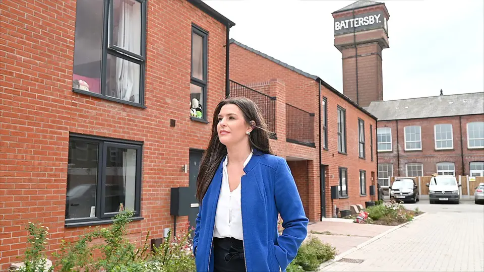 Female Walking In Front Of New Build Homes