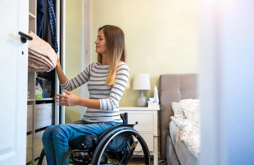 Woman in wheelchair getting something out of a cupboard 