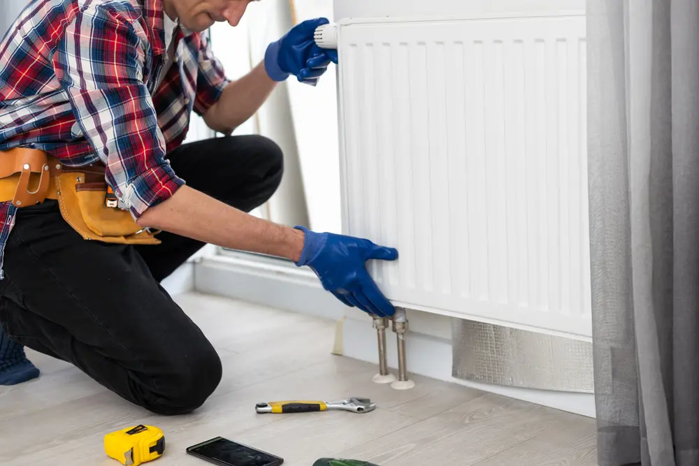 A person putting on a radiator to a wall