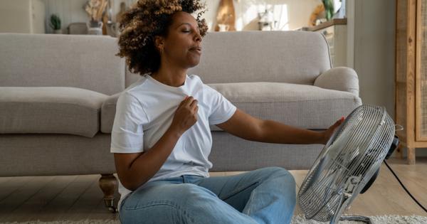 woman inside a housing with fan pointing to her looking warm
