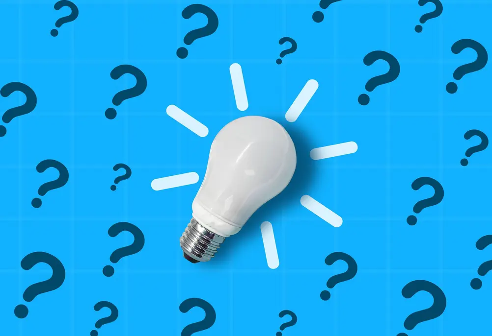 white light bulb against a blue background with black question marks across the background