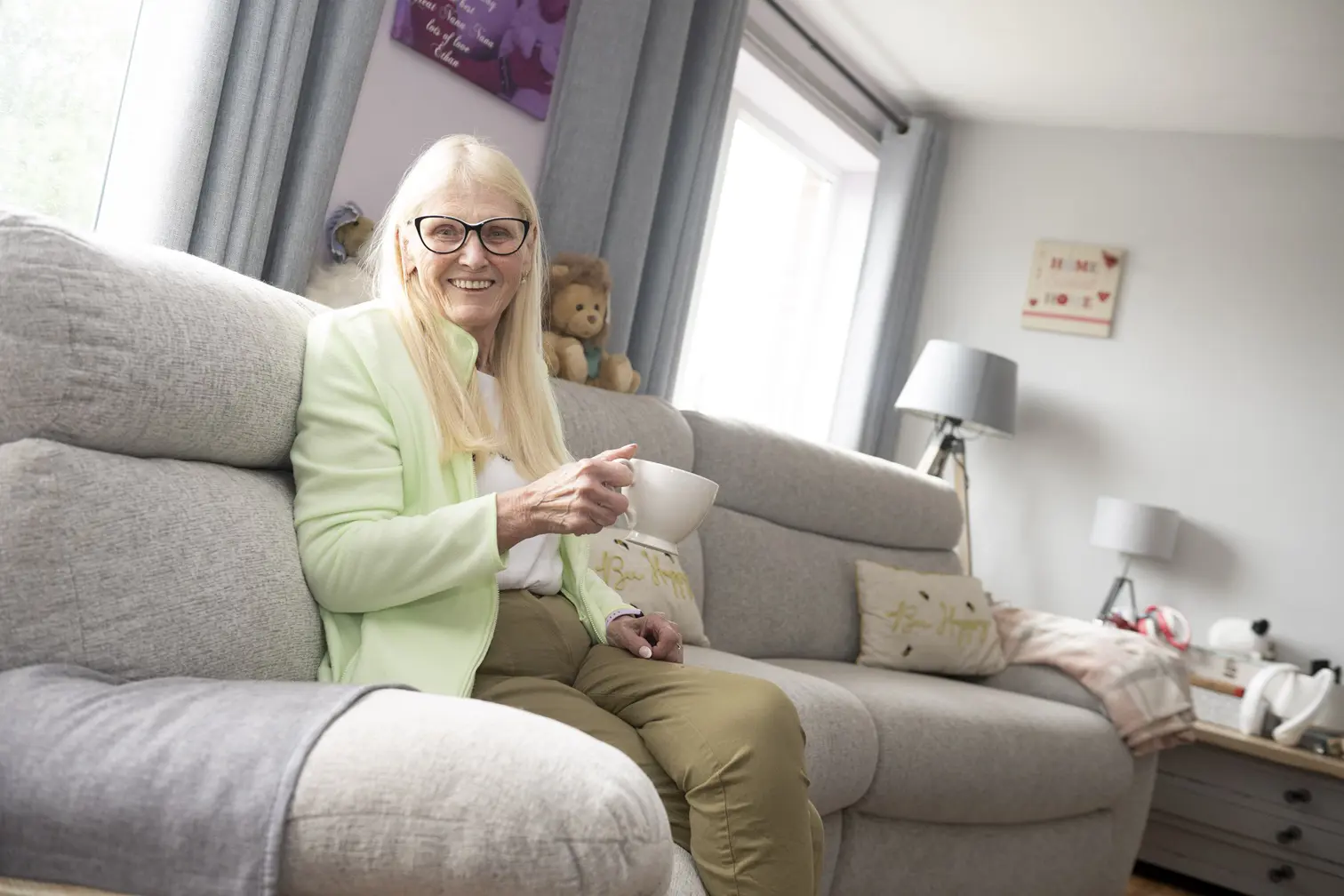 Female Customer Sat On Sofa Holding A Cup