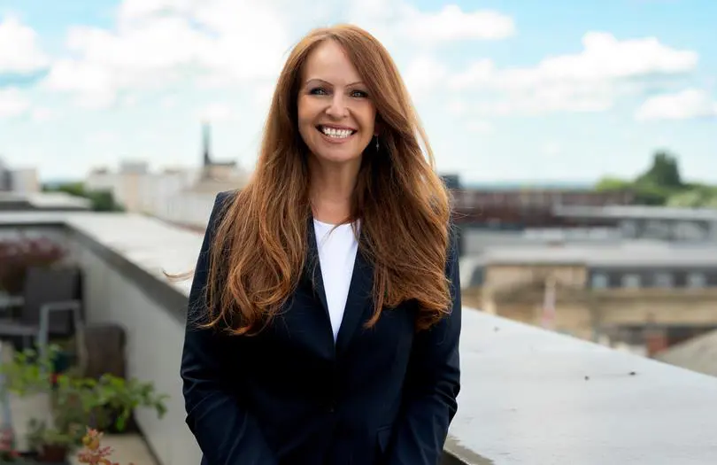 Carmel Chambers profile outside on balcony wearing a jacket