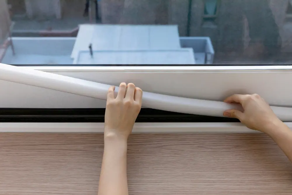 hands placing draft guard around a window frame