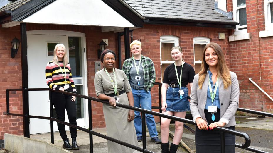 Group of people with green lanyards in front of building door