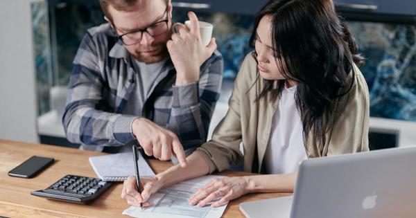 man and woman looking at papers on a desk with a laptop