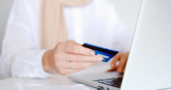 hand holding credit card while typing on laptop