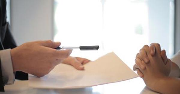 hands holding paper at a desk with other hands together