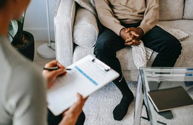 Woman writing on a notepad with man on sofa