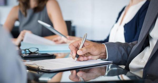 two woman in a board room with paper and pens