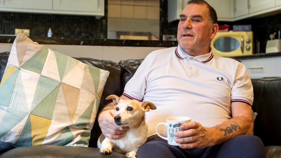 Man and dog sitting on sofa at home
