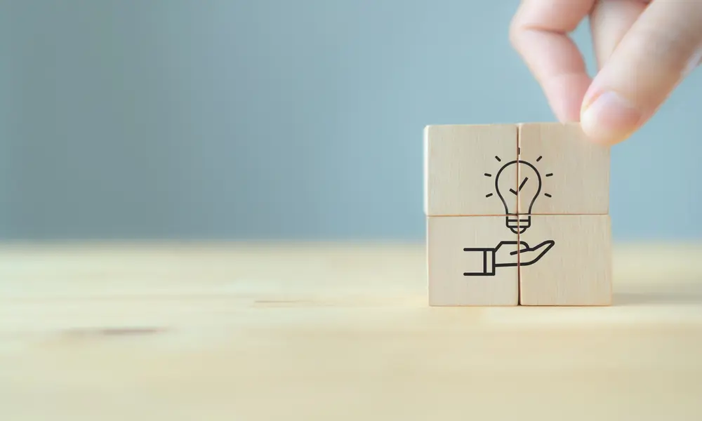 Hand placing blocks of a light bulb and hand