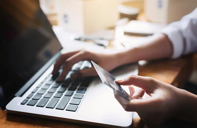 hand holding credit card and typing on laptop
