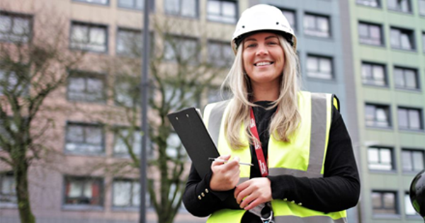 woman in hi-viz standing in front of tower block