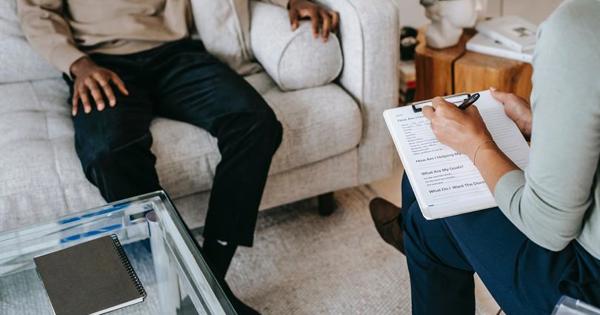 woman writing in notepad with man on sofa