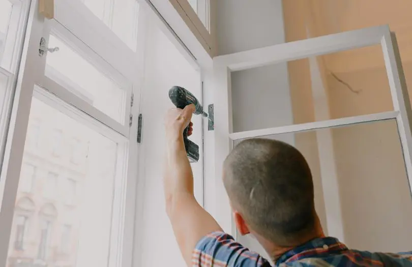 man with drill repairing a window