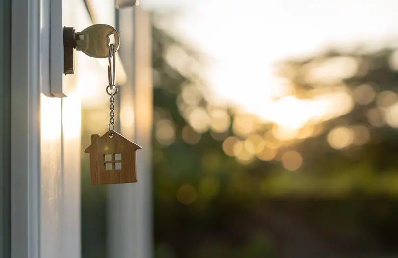 key with wooden house keychain in a door 