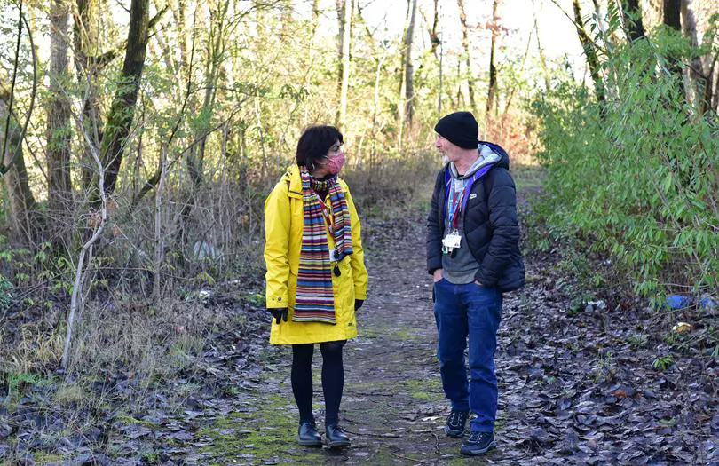 Woman in a yellow jacket in a park speaking to a man