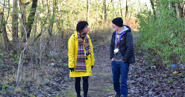 Woman in a yellow jacket in a park speaking to a man
