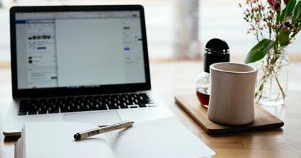 Laptop on a desk with mug and notepad