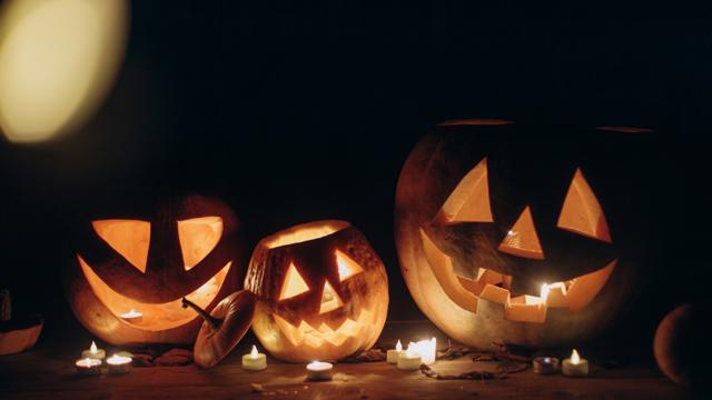 3 pumpkins with candles in a dark room