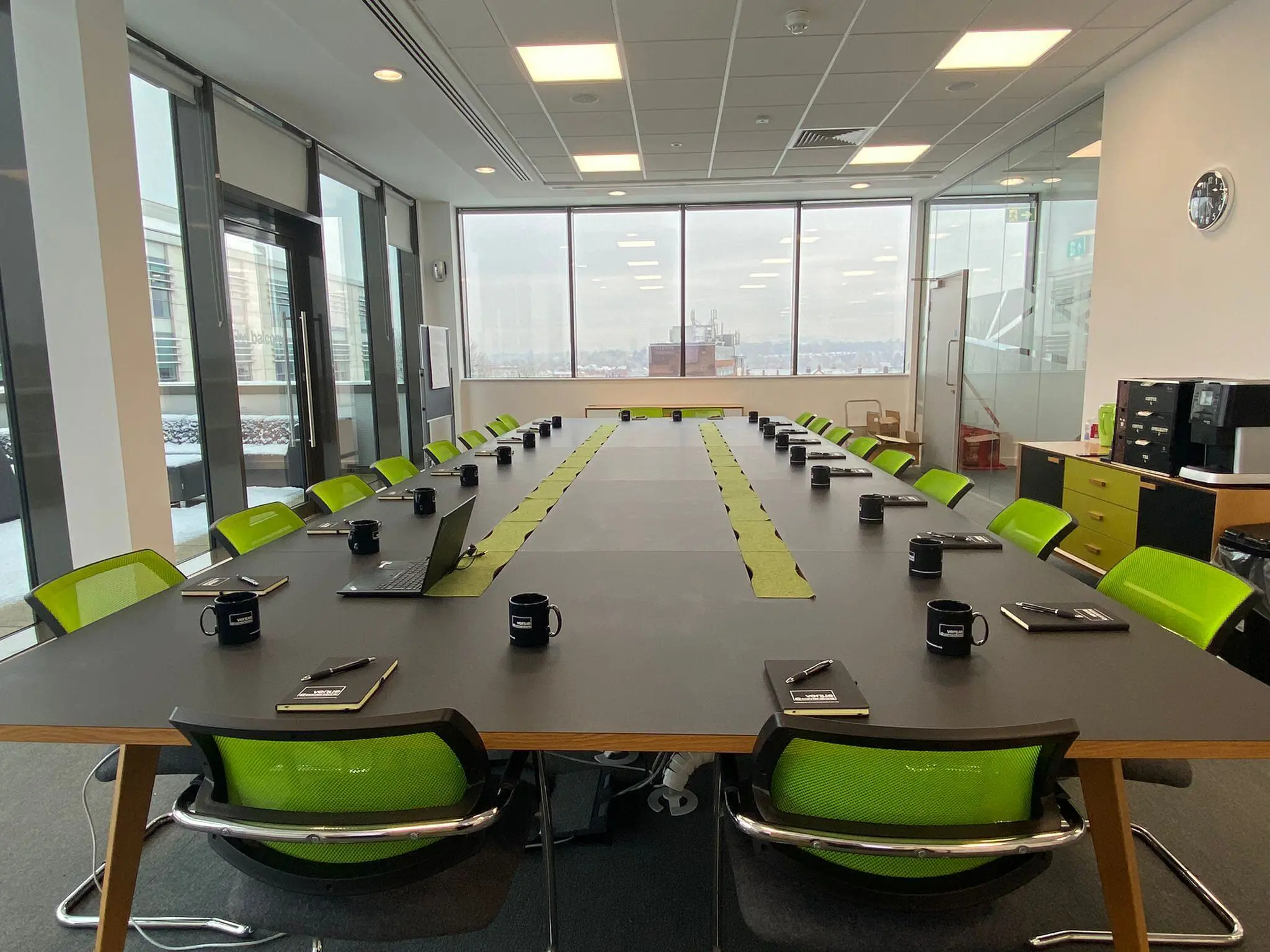 Top floor board room with green chairs and notepads in front of each chair