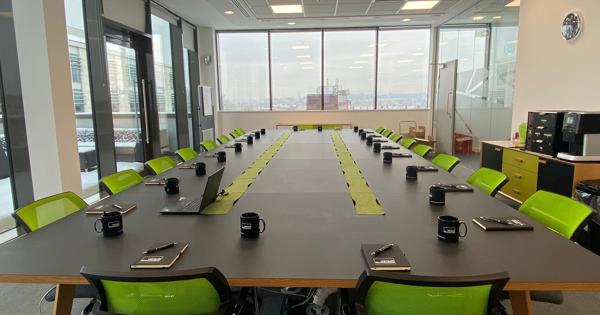 Top floor board room with green chairs and notepads in front of each chair