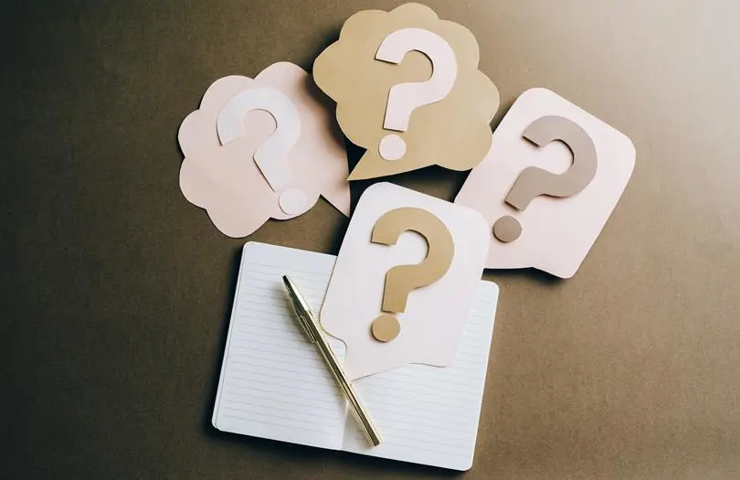 Question marks on paper notes around a notepad