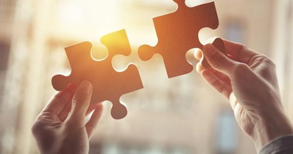 Two jigsaw pieces coming together in sunlight 