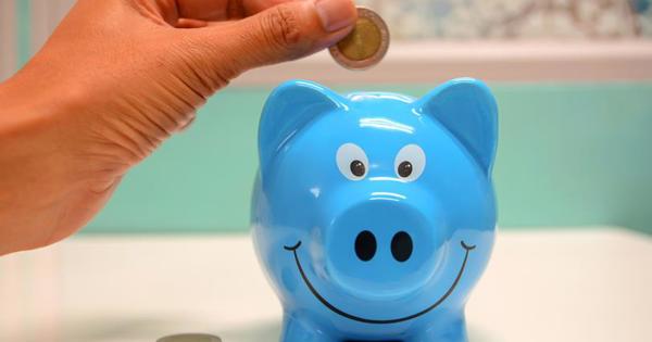 Blue piggy bank with hand placing coins into the top