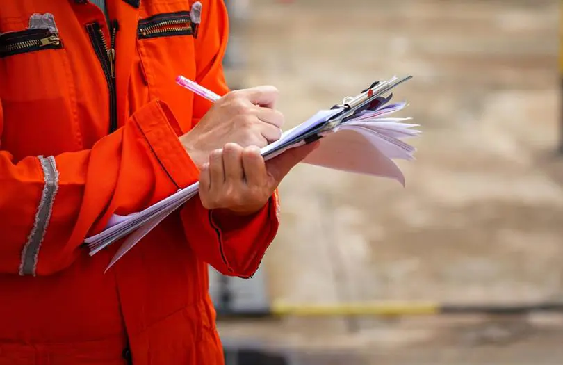 Person in red hi-viz writing on a notepad