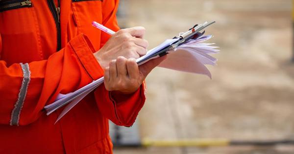 Person in red hi-viz writing on a notepad