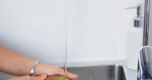 hands washing a fruit over a sink